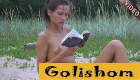 Красивая натуристка на пляже читает книгу - видео